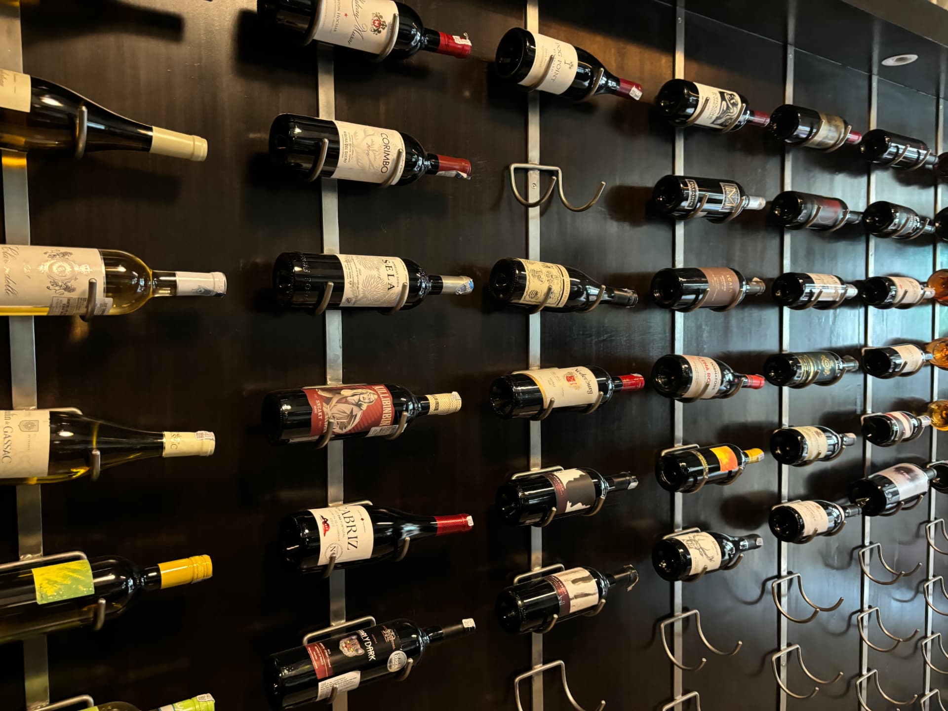 Rows of wine bottles displayed horizontally on a dark wall