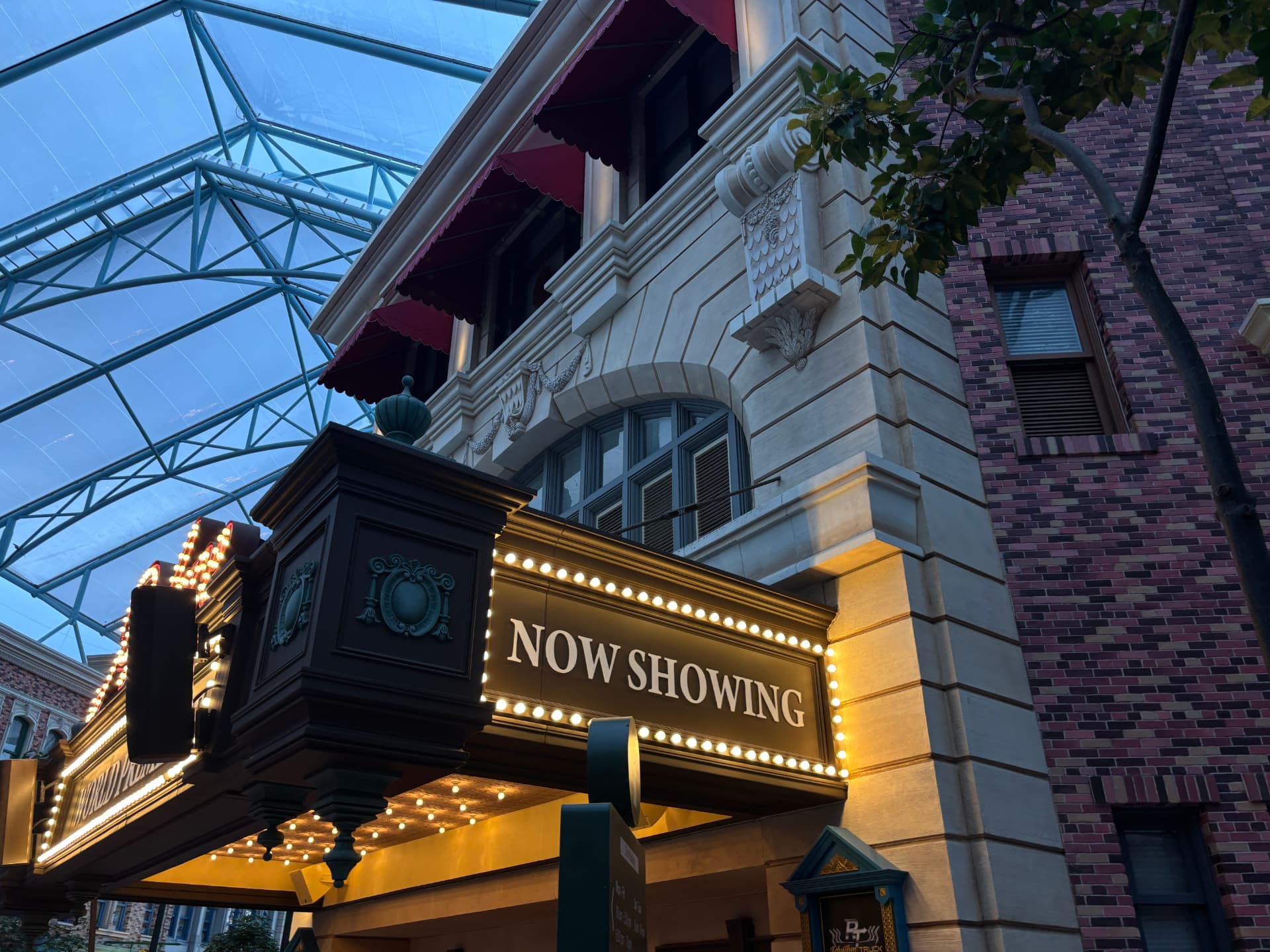 Now Showing theatre marquee lit against a glass-roofed street
